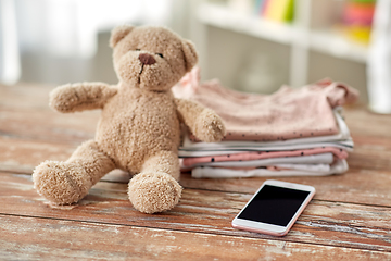 Image showing baby clothes, teddy bear toy and smartphone