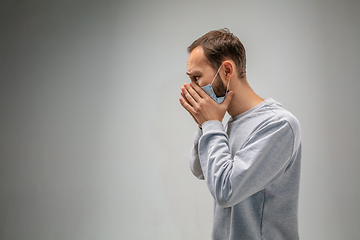 Image showing Caucasian man wearing the respiratory protection mask against air pollution and dusk on grey studio background