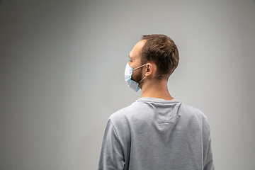 Image showing Caucasian man wearing the respiratory protection mask against air pollution and dusk on grey studio background