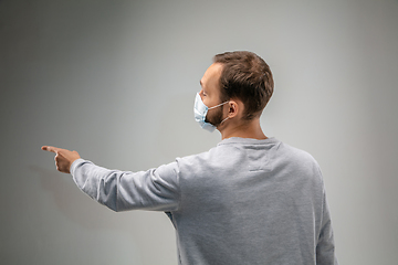 Image showing Caucasian man wearing the respiratory protection mask against air pollution and dusk on grey studio background