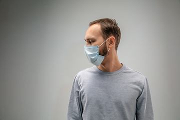 Image showing Caucasian man wearing the respiratory protection mask against air pollution and dusk on grey studio background