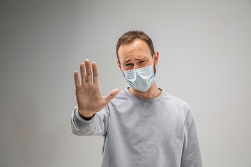 Image showing Caucasian man wearing the respiratory protection mask against air pollution and dusk on grey studio background
