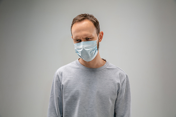 Image showing Caucasian man wearing the respiratory protection mask against air pollution and dusk on grey studio background