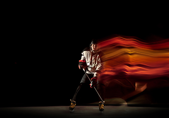 Image showing Young female hockey player with the stick on black background in neon light
