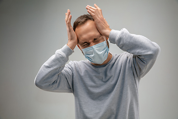 Image showing Caucasian man wearing the respiratory protection mask against air pollution and dusk on grey studio background