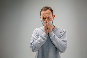 Image showing Caucasian man wearing the respiratory protection mask against air pollution and dusk on grey studio background