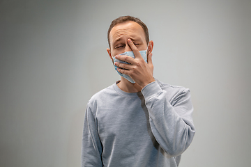 Image showing Caucasian man wearing the respiratory protection mask against air pollution and dusk on grey studio background