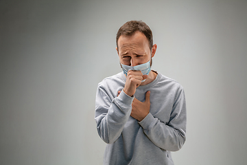 Image showing Caucasian man wearing the respiratory protection mask against air pollution and dusk on grey studio background