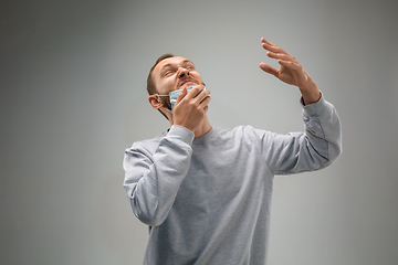 Image showing Caucasian man wearing the respiratory protection mask against air pollution and dusk on grey studio background