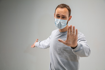 Image showing Caucasian man wearing the respiratory protection mask against air pollution and dusk on grey studio background