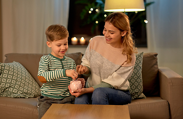 Image showing mother and little son with piggy bank at home