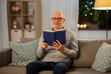 Image showing happy bald senior man on sofa reading book at home