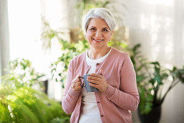 Image showing happy senior woman with cup of tea at home