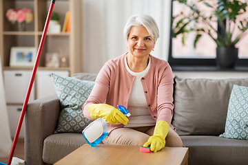 Image showing senior woman with detergent cleaning table at home