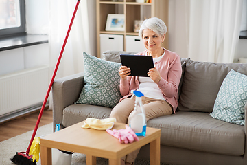 Image showing senior woman using tablet pc after cleaning home