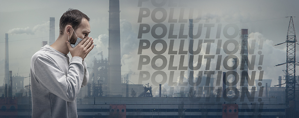 Image showing Caucasian man wearing the respiratory protection mask against air pollution and dusk with factories on background