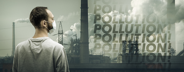 Image showing Caucasian man wearing the respiratory protection mask against air pollution and dusk with factories on background