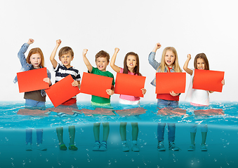 Image showing Group of children with blank red banners standing in water of melting glacier, global warming