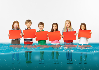 Image showing Group of children with blank red banners standing in water of melting glacier, global warming