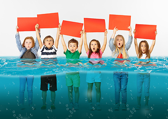 Image showing Group of children with blank red banners standing in water of melting glacier, global warming