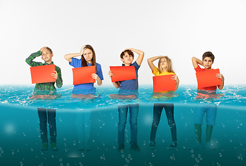 Image showing Group of children with blank red banners standing in water of melting glacier, global warming