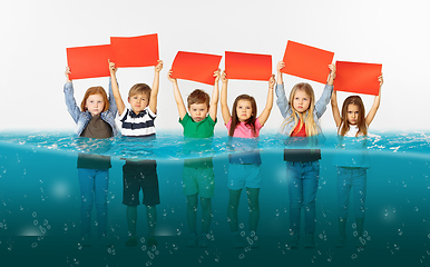 Image showing Group of children with blank red banners standing in water of melting glacier, global warming