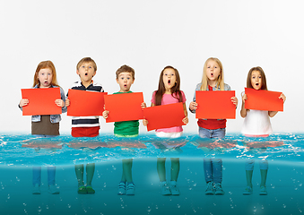 Image showing Group of children with blank red banners standing in water of melting glacier, global warming