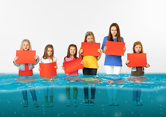 Image showing Group of children with blank red banners standing in water of melting glacier, global warming