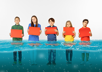 Image showing Group of children with blank red banners standing in water of melting glacier, global warming