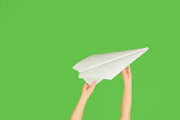 Image showing Hands holding the sign of paper airplane on green studio background