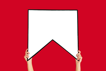 Image showing Hands holding the sign of bookmark on red studio background