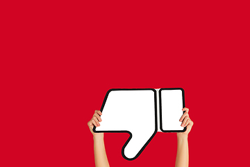 Image showing Hands holding the sign of dislike on red studio background