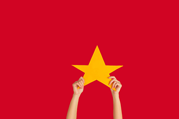 Image showing Hands holding the sign of star on red studio background