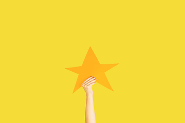 Image showing Hands holding the sign of star on yellow studio background