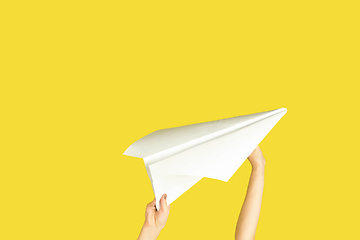 Image showing Hands holding the sign of paper airplane on yellow studio background