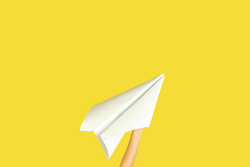 Image showing Hands holding the sign of paper airplane on yellow studio background