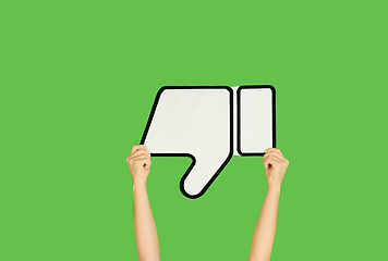 Image showing Hands holding the sign of dislike on green studio background