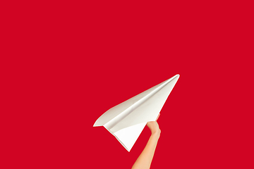 Image showing Hands holding the sign of paper airplane on red studio background