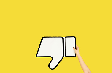 Image showing Hands holding the sign of dislike on yellow studio background