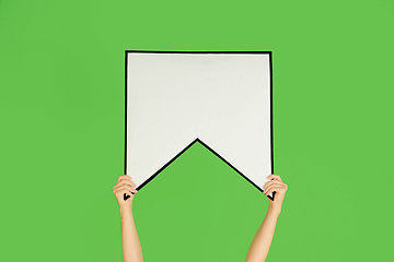 Image showing Hands holding the sign of bookmark on green studio background