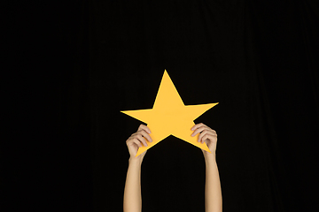 Image showing Hands holding the sign of star on black studio background