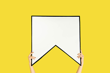 Image showing Hands holding the sign of bookmark on yellow studio background