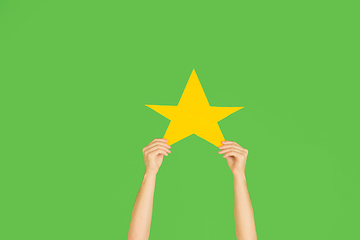 Image showing Hands holding the sign of star on green studio background