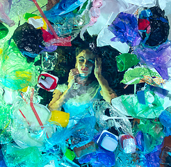 Image showing Woman drowning in ocean water under plastic recipients pile, environment concept