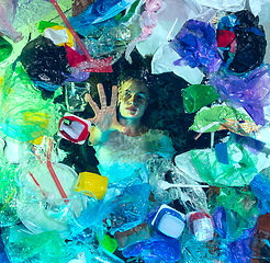 Image showing Woman drowning in ocean water under plastic recipients pile, environment concept