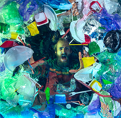 Image showing Man drowning in ocean water under plastic recipients pile, environment concept