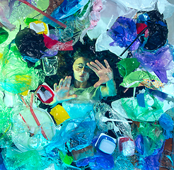 Image showing Woman drowning in ocean water under plastic recipients pile, environment concept