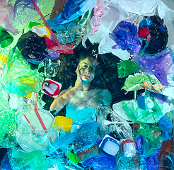 Image showing Woman drowning in ocean water under plastic recipients pile, environment concept