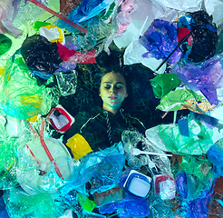 Image showing Woman drowning in ocean water under plastic recipients pile, environment concept