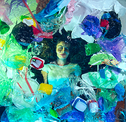 Image showing Woman drowning in ocean water under plastic recipients pile, environment concept